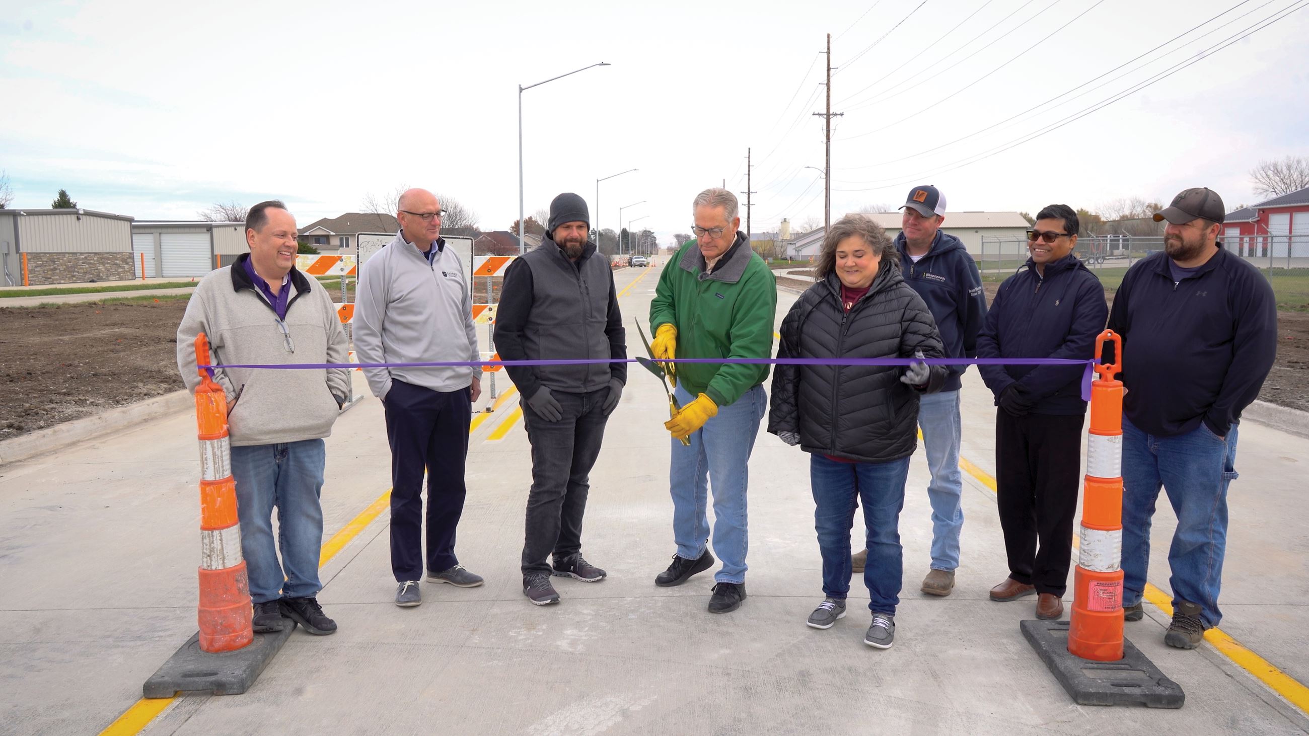 Indianola City Council Member Steve Richardson cuts purple ribbon alongside group of individuals.