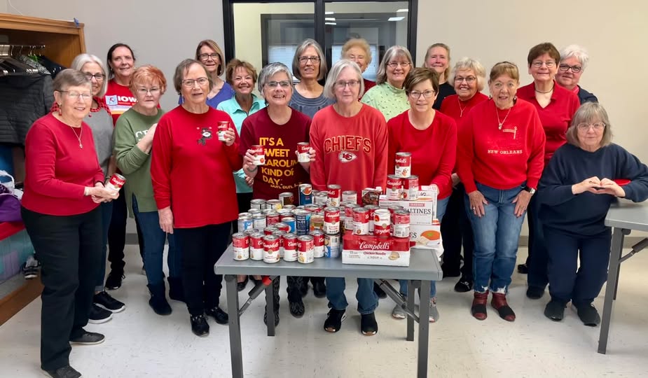 a group of line dancers stand behind items they collected for the local food pantry