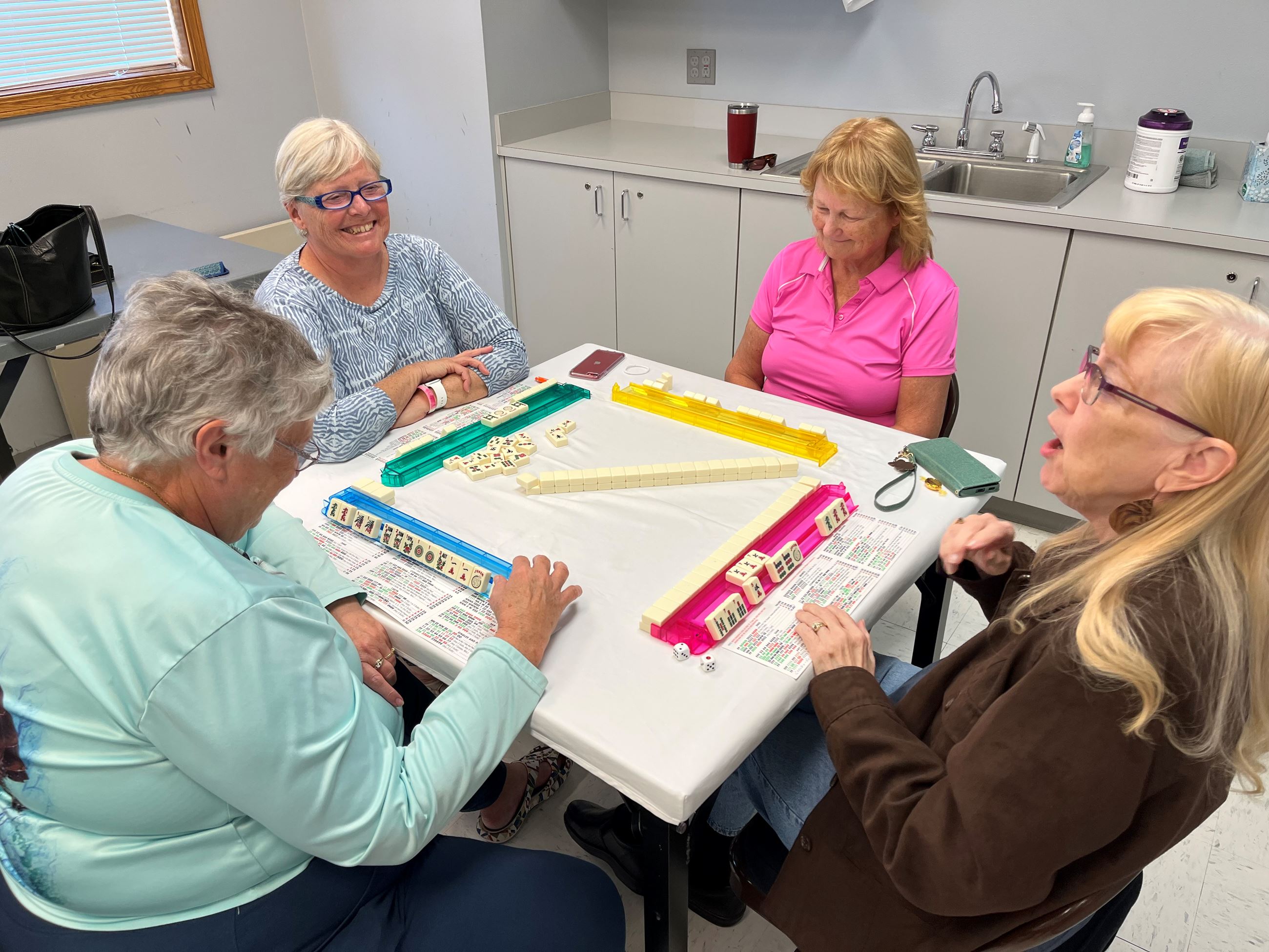women sitting at a table playing Mah Jongg