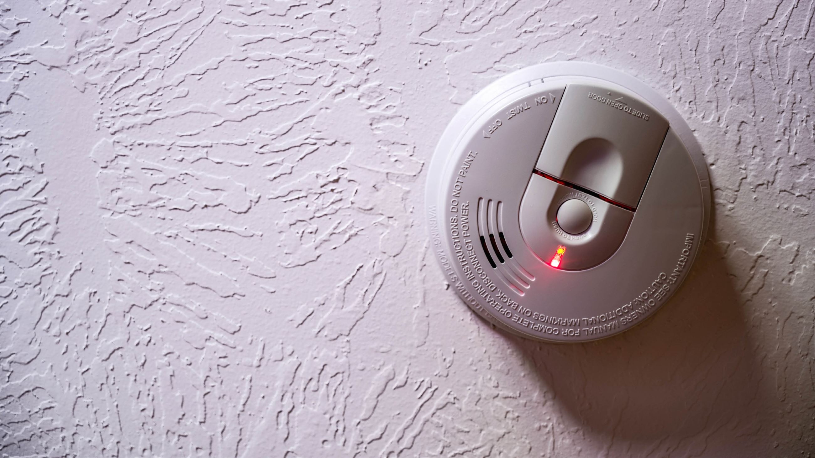 A functioning smoke alarm installed on the ceiling of a room in a building.