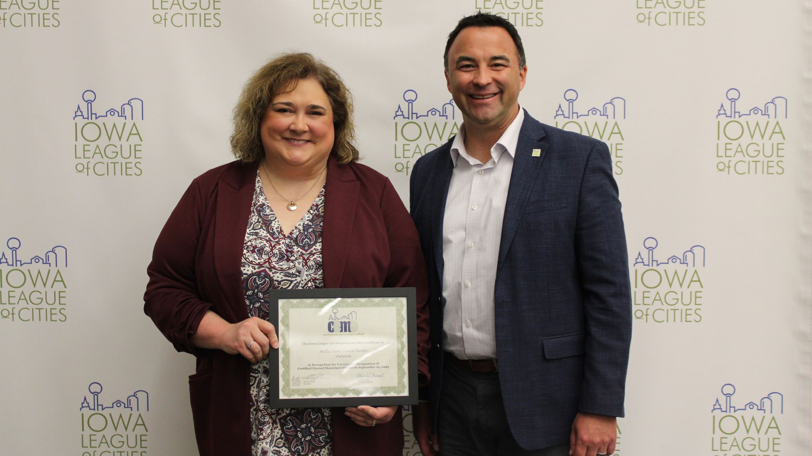Mellisa Sones (left) holds a certificate for receiving CEMO designation by the Iowa League of Cities