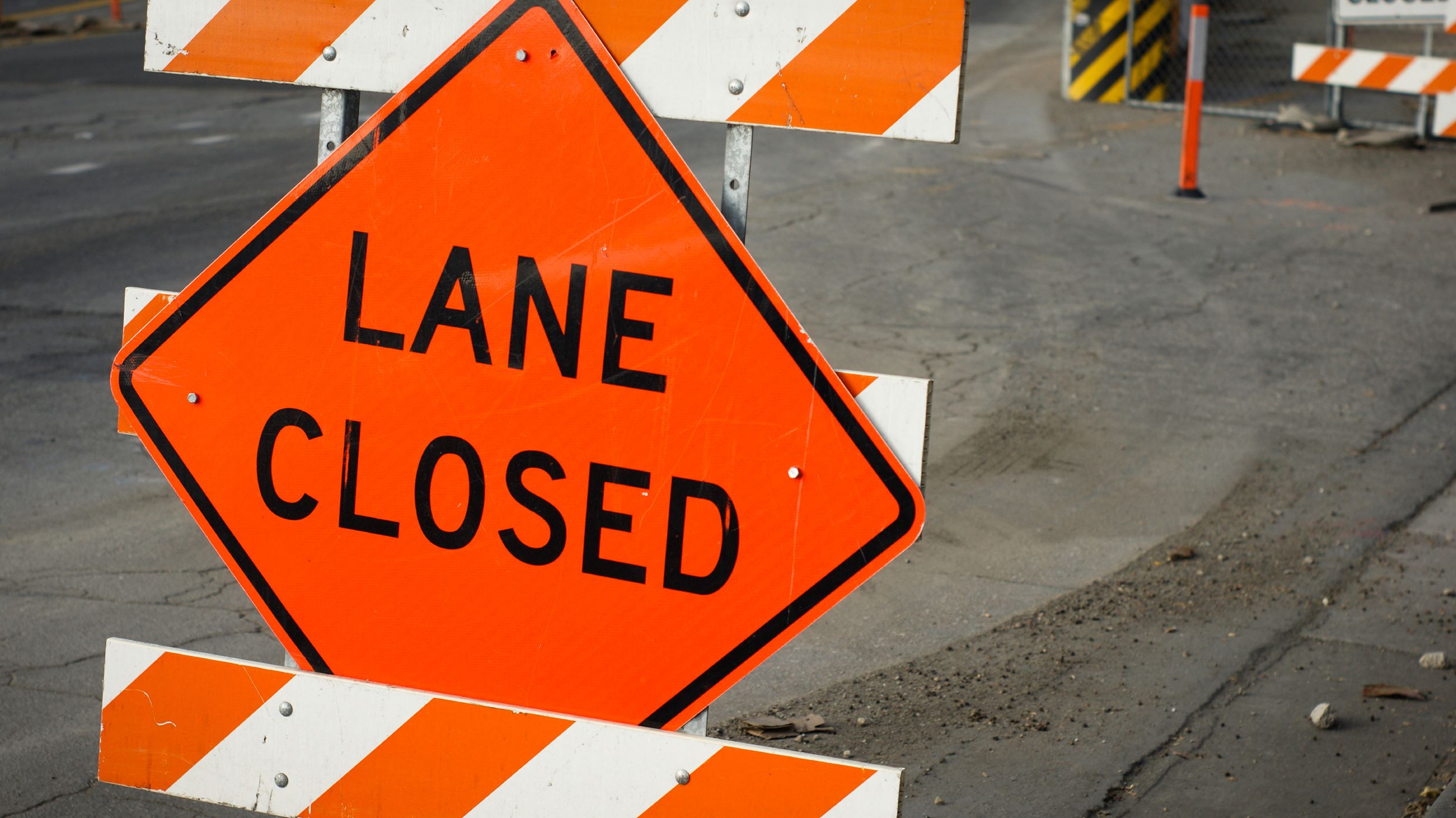 A lane closed sign stands upright along a street.