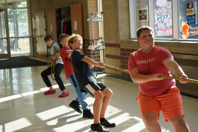 A group of middle school boys pull on a tug of war rope at The Zone after-school program