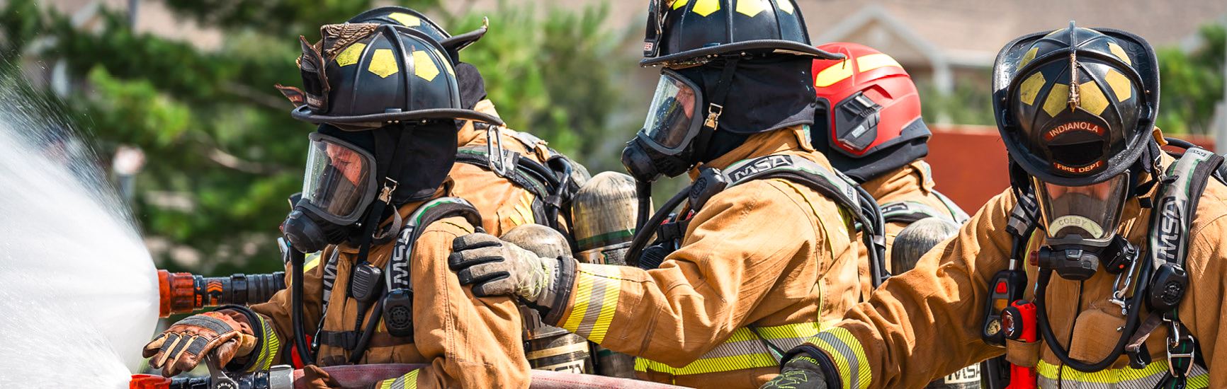 A team of Indianola Firefighters conduct training while holding a hose to put out a fire.