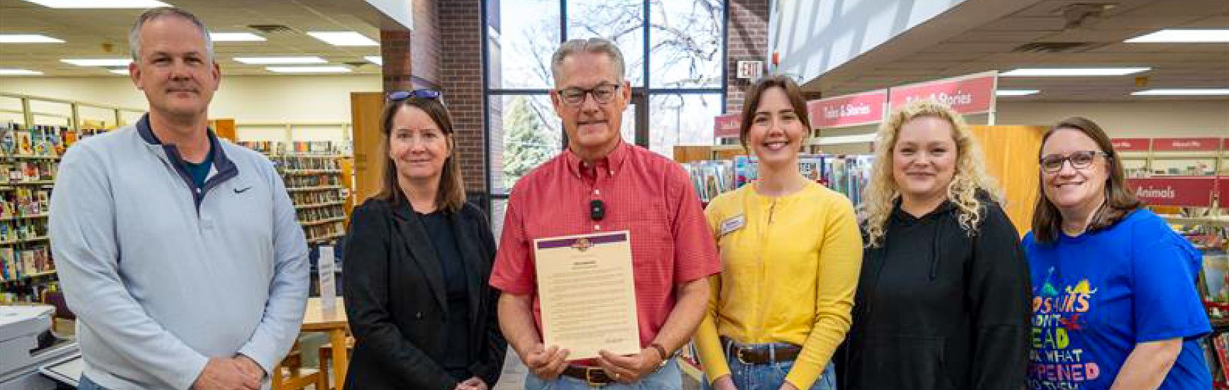A group of Indianola Public Library employees, Mayor and Culture/Rec Chief smile for a photo.