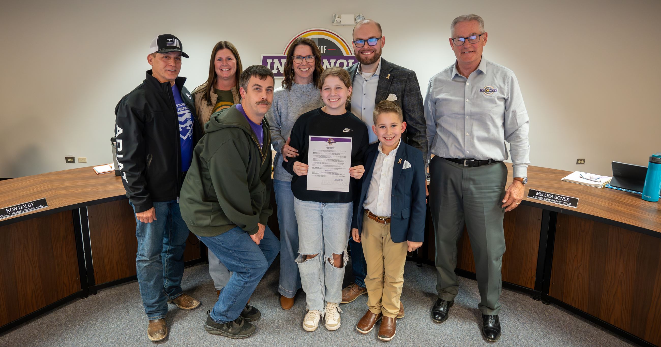 Relatives of Madalynn Snow stand beside Indianola Mayor Steve Richardson, holding a proclamation.
